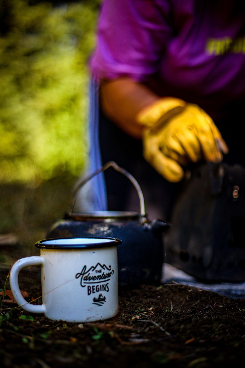 Enamel camping mug and kettle on the woodland floor